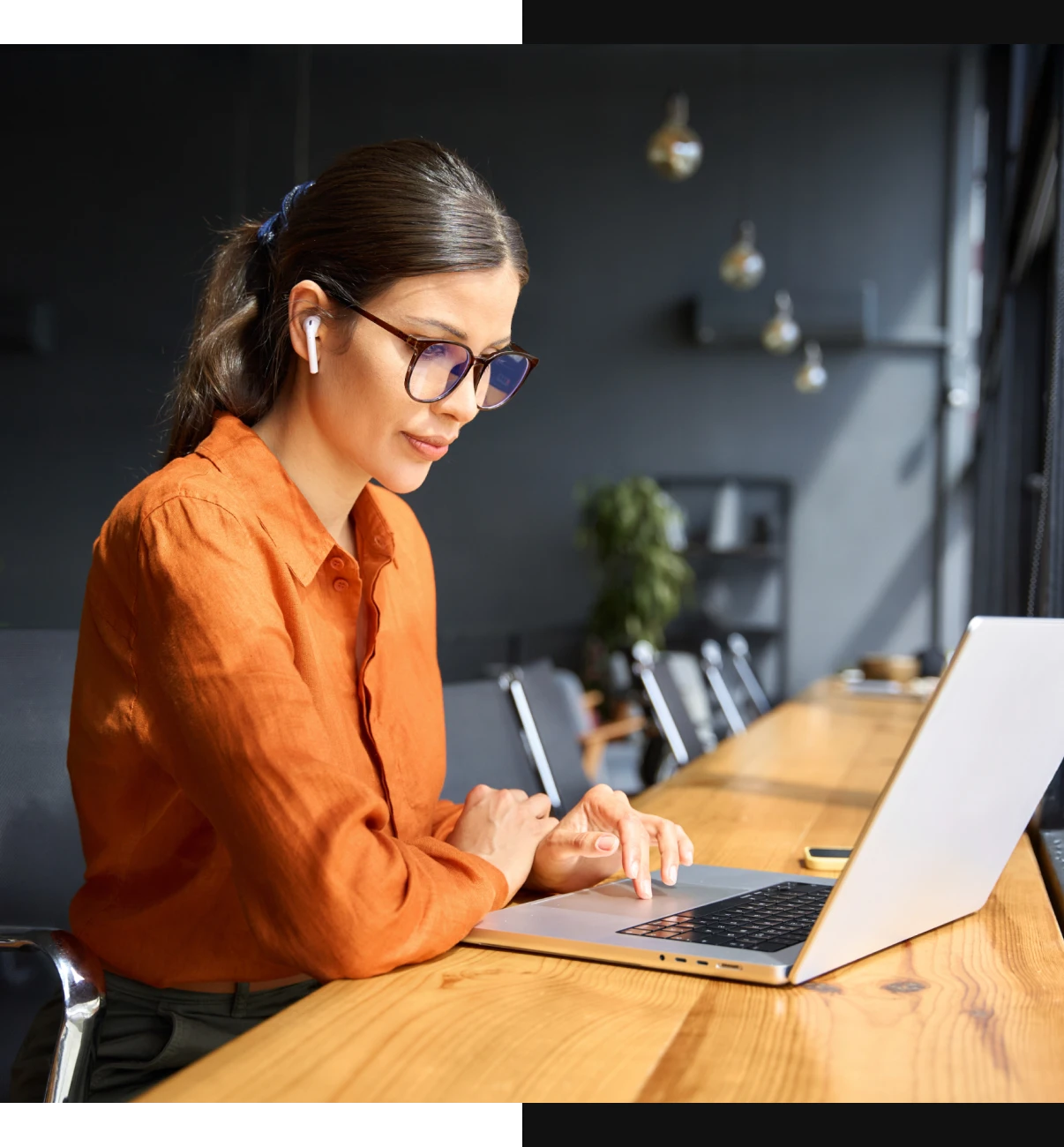 Woman in orange shirt typing on laptop